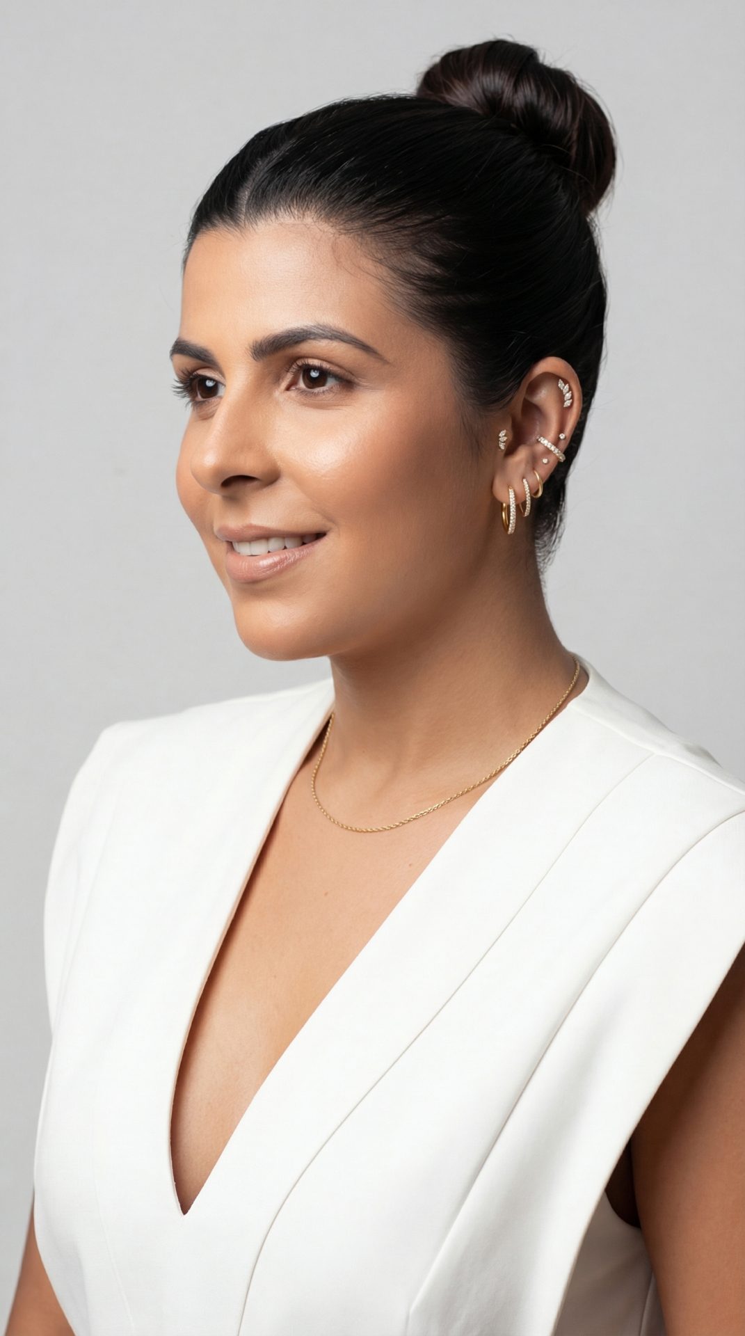 Mulher com brincos e piercings de ouro em composição de estética auricular na Luquini Clinic
